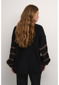 Maglione over-size di un blu navy scuro realizzato in morbido tessuto a maglia, con maniche ampie decorate da strisce marroni e orlo a costine.