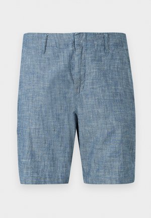 Μπλε σορτς από ύφασμα chambray με θηλιές για ζώνη και μπροστινό κλείσιμο με φερμουάρ, παρουσιασμένα επίπεδα σε λευκό φόντο.