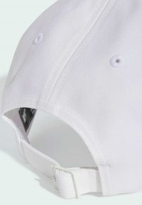 Biela bavlnená čiapka s zakriveným šiltom, s prešitým textúrovaním, nastaviteľným popruhom a ventilačnými otvormi. Zadný pohľad ukazuje kovanie popruhu.