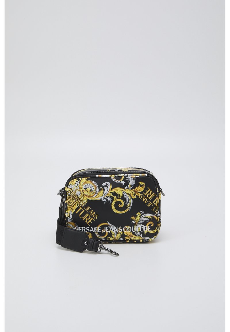Mała czarna torebka na ramię z złotymi i białymi wzorami w stylu barokowym oraz napisem "Versace Jeans Couture", wyposażona w odpinany czarny pasek.