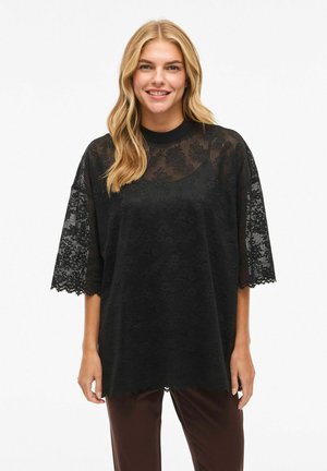Zwarte blouse met kanten bovenkant, korte brede mouwen en een gegolfde zoom. Doorschijnende stof met bloemmotieven en een ronde halslijn.