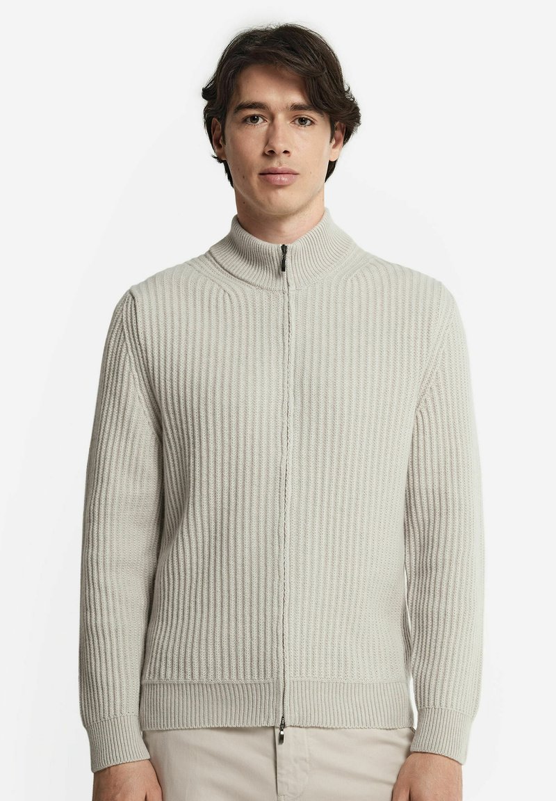 Ljusgrå zip-up-tröja med ribbad textur, hög krage och långa ärmar. Har en framdragbar dragkedja och är tillverkad av ett mjukt material.