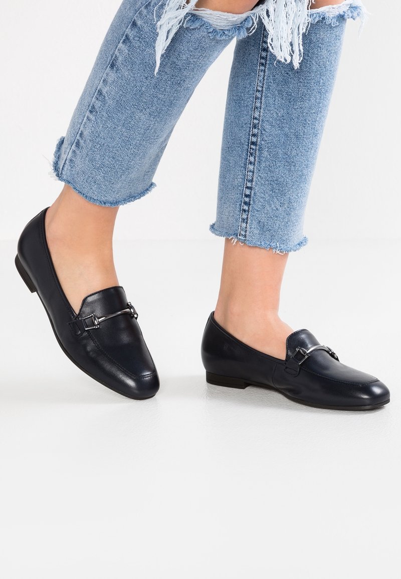 Mocassins en cuir bleu marine au design élégant, dotés d'un accent décoratif en métal argenté et d'un talon bas légèrement contourné.