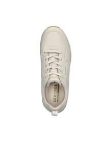 Zapatilla color beige claro con parte superior de cuero sintético liso, cordones blancos, marca dorada y una plantilla texturizada. Presenta una lengüeta en el talón.