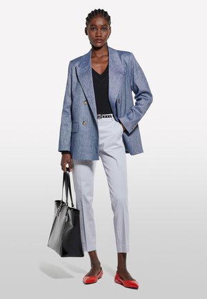 Blazer bleu clair à double boutonnage, top noir à col en V, pantalon tailleur gris clair, sac fourre-tout noir et ballerines rouges. Texture lisse et design ajusté.
