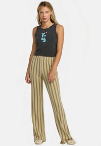 Tmavosivé tielko bez rukávov s tyrkysovým grafickým motívom, skombinované s béžovými širokými nohavicami s pruhmi v zelenej a zlatej farbe.