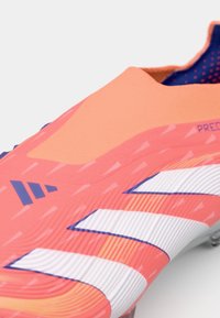 Scarpa da calcio rosa brillante con tomaia texturizzata, strisce bianche e dettagli blu. Design elegante con una vestibilità aderente per le prestazioni sul campo.