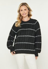 Pulover tricotat negru cu dungi orizontale albe. Prezintă un material texturat și un guler rotund. Mâneci complete cu manșete ribbate.