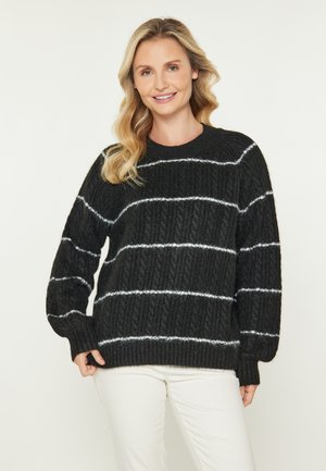 Maglione nero lavorato a maglia con strisce orizzontali bianche. Presenta un tessuto texturizzato e un collo rotondo. Maniche lunghe con polsini a coste.