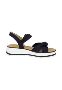 Sandalía azul marino con detalle de nudo, correas elásticas y una suela de plataforma blanca que presenta una franja negra. Texturizada en material suave para mayor comodidad.