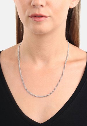 Silberne Metallkettenschmuck, flaches Design, mittlere Dicke, glatte Textur, getragen über einem schwarzen V-Ausschnitt-Shirt.