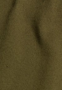 Gros plan sur un tissu tricoté vert olive montrant une fine texture côtelée et de légers plis dans le matériau.