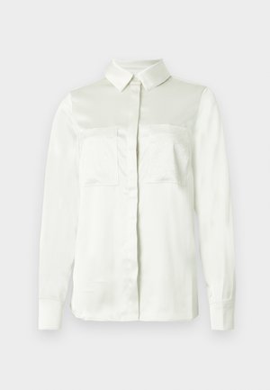 Cămașă albă cu mâneci lungi din material fin, cu guler clasic, două buzunare decorative în față și accente texturate pe buzunare.