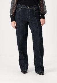 Σκούρες τζιν παντελόνες με φαρδιά πόδια και ψηλή μέση, διαθέτοντας μπροστινές τσέπες, αντίθετη ραφή και καθαρή καμπή στο τελείωμα.