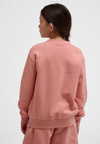 Rosa sweatshirt med rund nacke och långa ärmar, gjord av mjukt tyg. Har ribbade manschetter och nederkant, avslappnad passform och minimala sömnadsdetaljer.