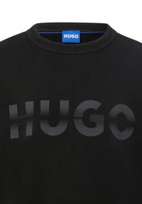 Felpa nera con colletto a coste. Presenta un grande logo "HUGO" stampato sul petto in tonalità sfumate. Texture soffice.