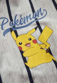 Grafica di Pikachu giallo su tessuto grigio, con testo "Pokémon" blu e strisce verticali scure. Texture morbida, design cartoonesco.