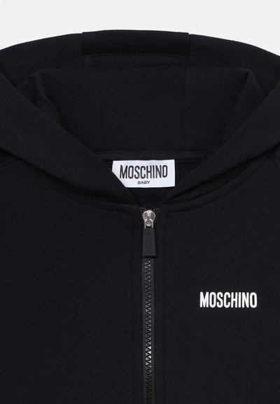 Čierna mikina na zips vyrobená z mäkkej látky, s bielym logom "MOSCHINO" na prednej strane a klasickým dizajnom kapucne.