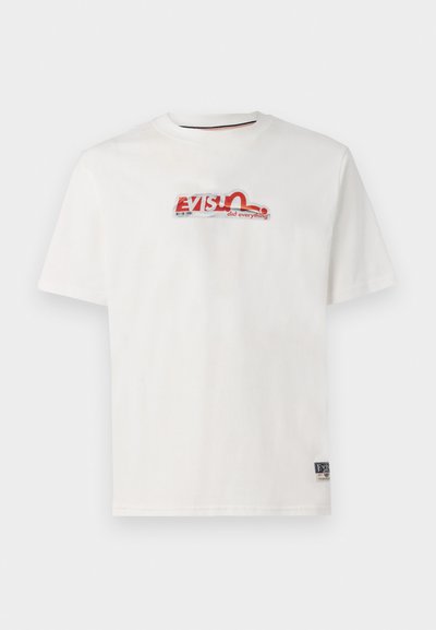 T-shirt en coton blanc avec un col ras du cou. Présente un logo imprimé coloré en texte rouge et bleu, ainsi qu'une petite étiquette de marque sur le côté.