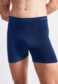 Námořnické modré pánské boxerky vyrobené z měkkého materiálu, s těsným střihem, elastickým páskem a minimálním logem nahoře.
