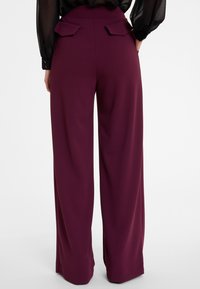 Bordeaux brede pijpen broek met een gladde textuur, voorzien van twee achterzakken en geplooide details bij de tailleband.