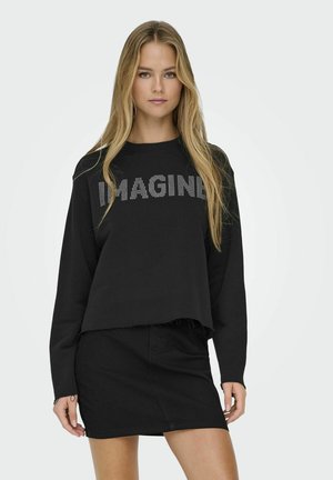 Felpa nera a maniche lunghe con "IMAGINE" in strass, caratterizzata da un design cropped e orlo grezzo, abbinata a una gonna di jeans nera.