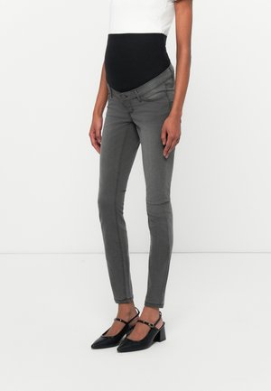 Maternity skinny jeans in grey, featuring a black elastic over-bump panel, five-pocket design, and slim-fit silhouette. Paired with black heels.