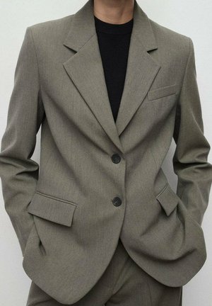 Blazer gris claro hecho de tela texturizada. Con solapa clásica, dos bolsillos frontales y diseño de un solo botón con dos botones.
