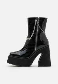 Černé lakované kotníkové boty s krokodýlí texturou, zipem, stříbrným řetízkem a silnou černou platformou s křivkovým tvarem.