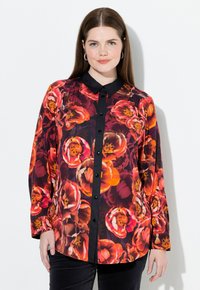 Langærmet skjorte med et livligt blomsterdesign i nuancer af rød, orange og pink, med en sort krave og knaplukning foran.
