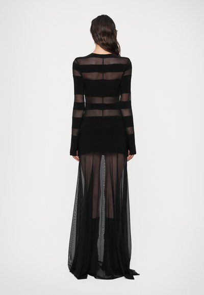 Dolga črna obleka s prosojnimi paneli s horizontalnimi črtami, prilegajočim se bodicem in izjemno krilo. Gladko teksturo z elegantno silhueto.