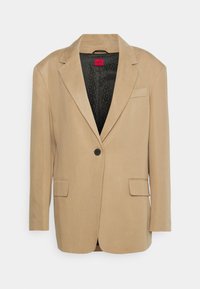Blazer beige con un diseño estructurado, cierre de un solo botón, dos bolsillos frontales y un forro negro con motivos. Textura suave.
