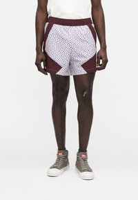 Shorts à motifs avec un design géométrique en blanc et bleu avec des accents bordeaux, fabriqués en tissu léger, et une taille élastique.