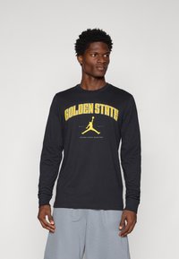 Svart langermet T-skjorte med "GOLDEN STATE" og en gul Jordan-logo. Myk bomullsstoff med rund hals og vanlig passform.