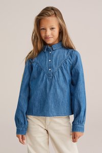 Denim garšs piedurkņu krekls ar pogājamu apkakli, krokotu detaļu krūšu rajonā un savākta piedurknes. Gaiši zila krāsa ar maigu tekstūru.