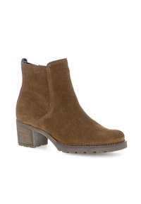 Bottine en daim marron avec des panneaux élastiques sur les côtés, un bout arrondi et un talon en bloc texturé. Présente des détails cousus et une semelle en caoutchouc.