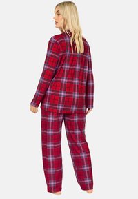 Röd och lila rutig pyjamasuppsättning, med långa ärmar och löst sittande byxor, tillverkad av mjukt tyg med en lätt borstad yta.