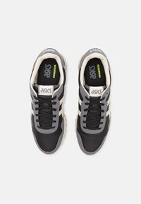 Black and gray athletic shoes with three white stripes, a textured finish, lace-up design, and cushioned insole labeled "EZ-FOAM."