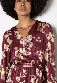Bordeauxfarbendes Blumen-Wickelkleid mit langen Ärmeln, V-Ausschnitt, Satin-Textur und passendem, tailliertem Gürtel.