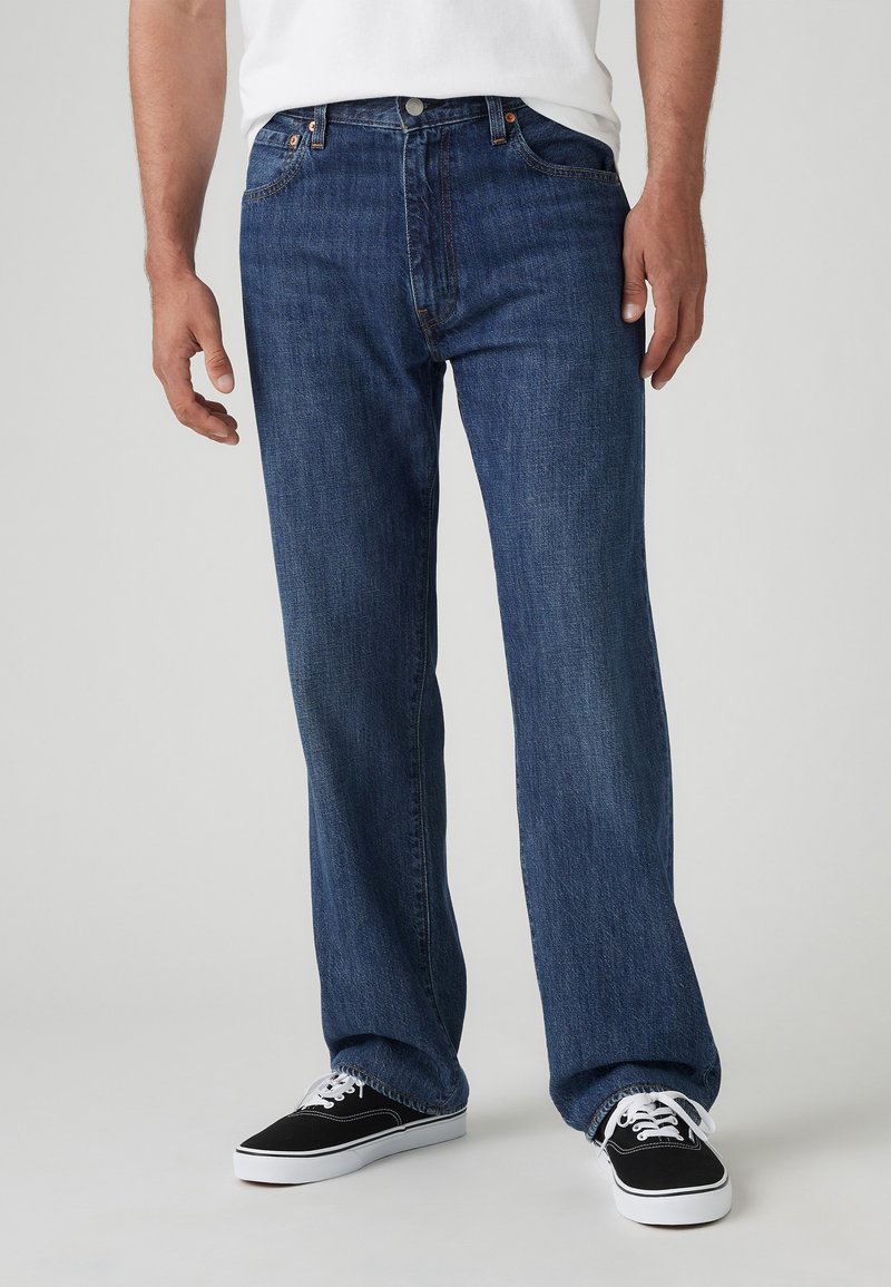 Jeans en denim bleu foncé, coupe droite avec design à cinq poches. Comprend une fermeture à bouton, des coutures discrètes et une taille confortable.