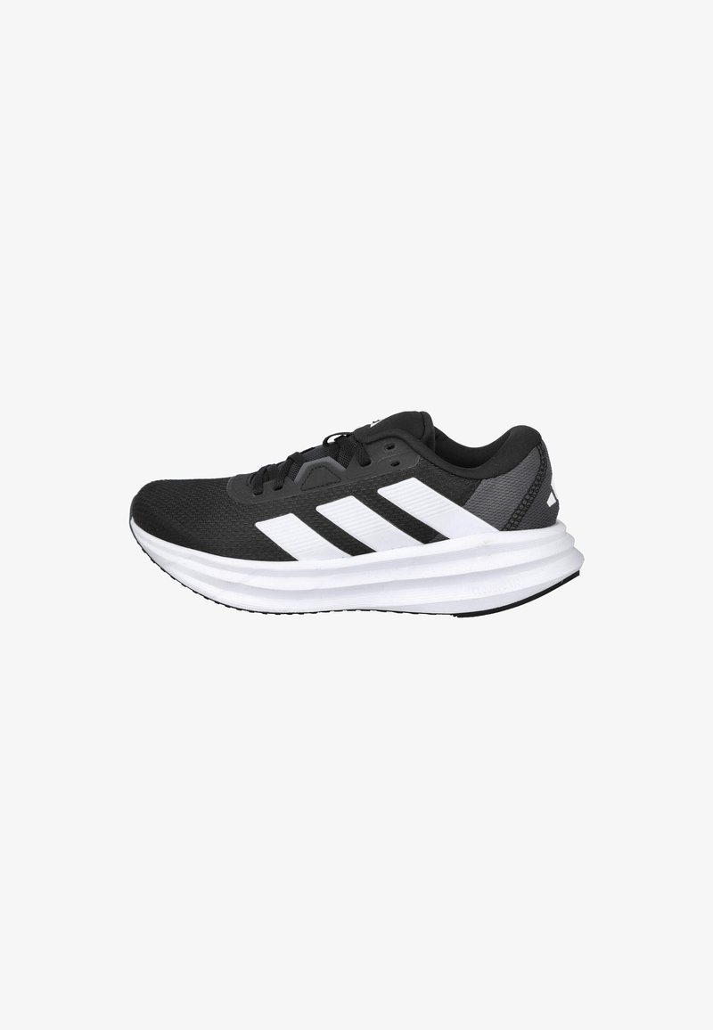 Zapatilla deportiva negra con parte superior de malla ligera, que presenta tres franjas blancas, una plantilla blanca acolchada y suela exterior de goma texturizada.