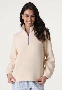 Maglione in pile color crema con collo a mezza zip, maniche lunghe e tessuto morbido. Presenta un dettaglio di cerniera azzurra chiaro.