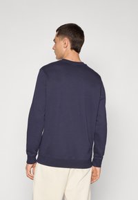 Navy sweatshirt with long sleeves and a crew neckline, featuring ribbed cuffs and a ribbed hem, made of smooth, textured fabric.