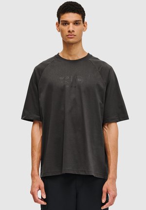 Czarnoszary, oversize T-shirt z miękkiego materiału, z krótkimi rękawami raglanowymi i delikatnymi tłoczonymi detalami logo z przodu.