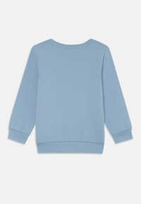 Lys blå hettegenser med rund hals, lange ermer og ribbestrikkede mansjetter. Laget av mykt stoff med en jevn tekstur.