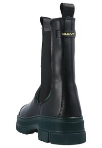 Black leather Chelsea boot with elastic side panels and a green rubber outsole. Features a pull tab and gold Gant branding near the heel.