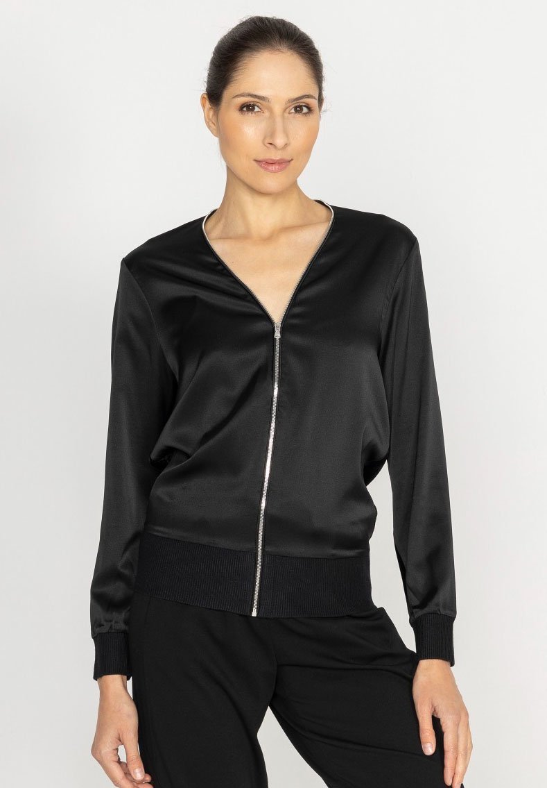 Czarna satynowa kurtka bomberka z zamkiem z przodu, dekoltem w serek i ściągaczami na rękawach. Miękka w dotyku i luźnego kroju, idealna na co dzień.
