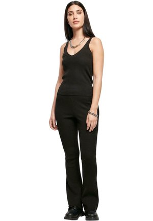 Black ribbed knit tank top and flared pants set with v-neckline. Features a silver chain necklace. Smooth texture and fitted design.