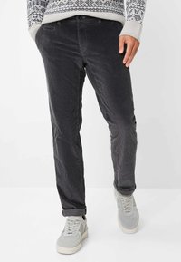 Pantaloni grigi in corduroy con texture a costine, dotati di tasche laterali e orli arrotolati, abbinati a sneakers grigie chiare.