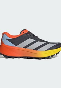 Chaussure de trail running noire et grise avec talon orange, semelle jaune, lacets noirs et semelle agressive pour une traction optimale en extérieur.